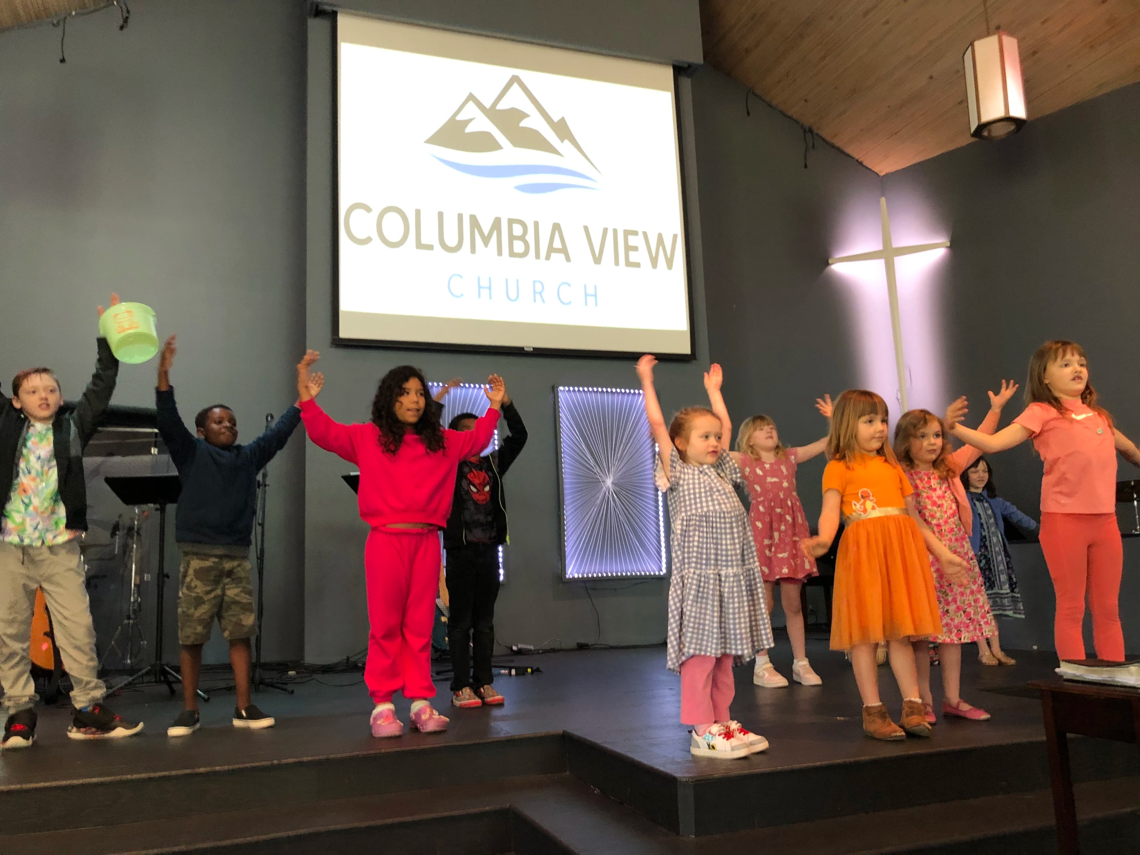 A crowd of kids on stage dancing to a song