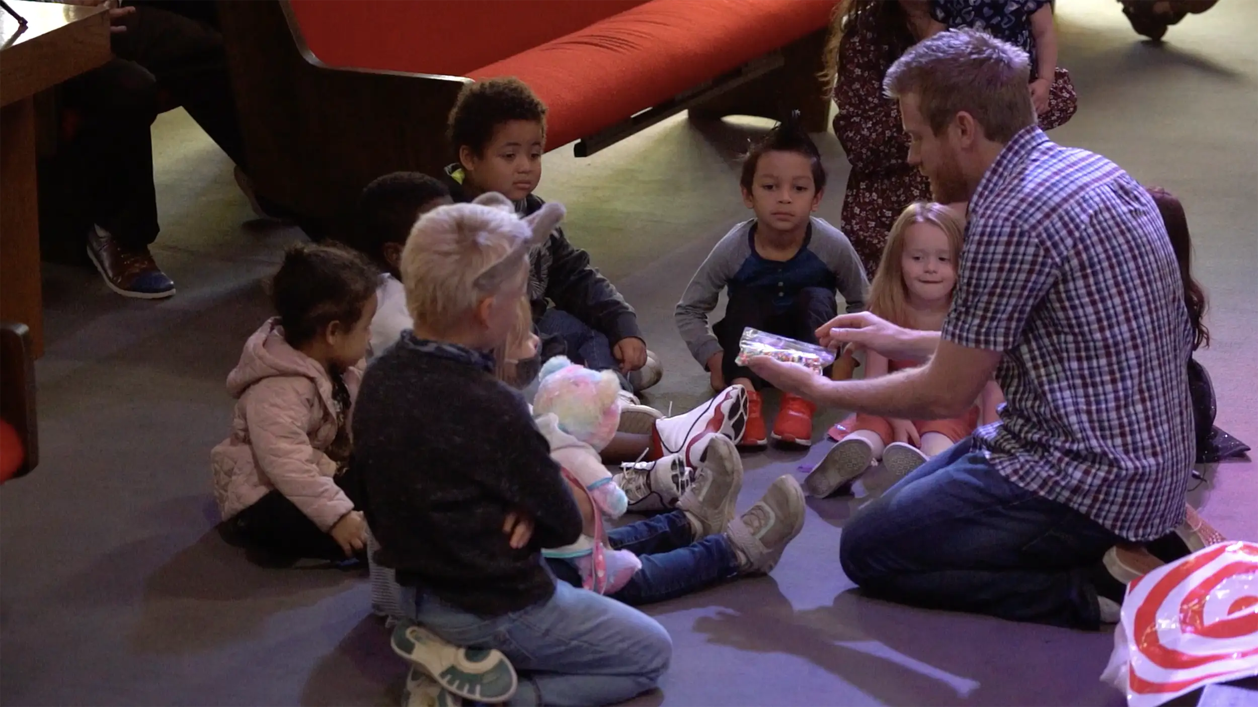 A pastor teaching a crowd of kids gathered around him