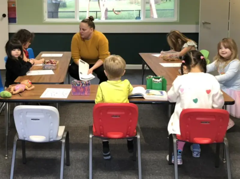 Teacher instructing kids sitting around a table