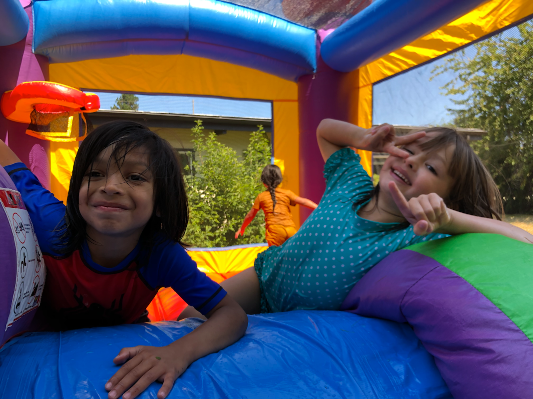 Two kids smiling while enjoying a bounce house